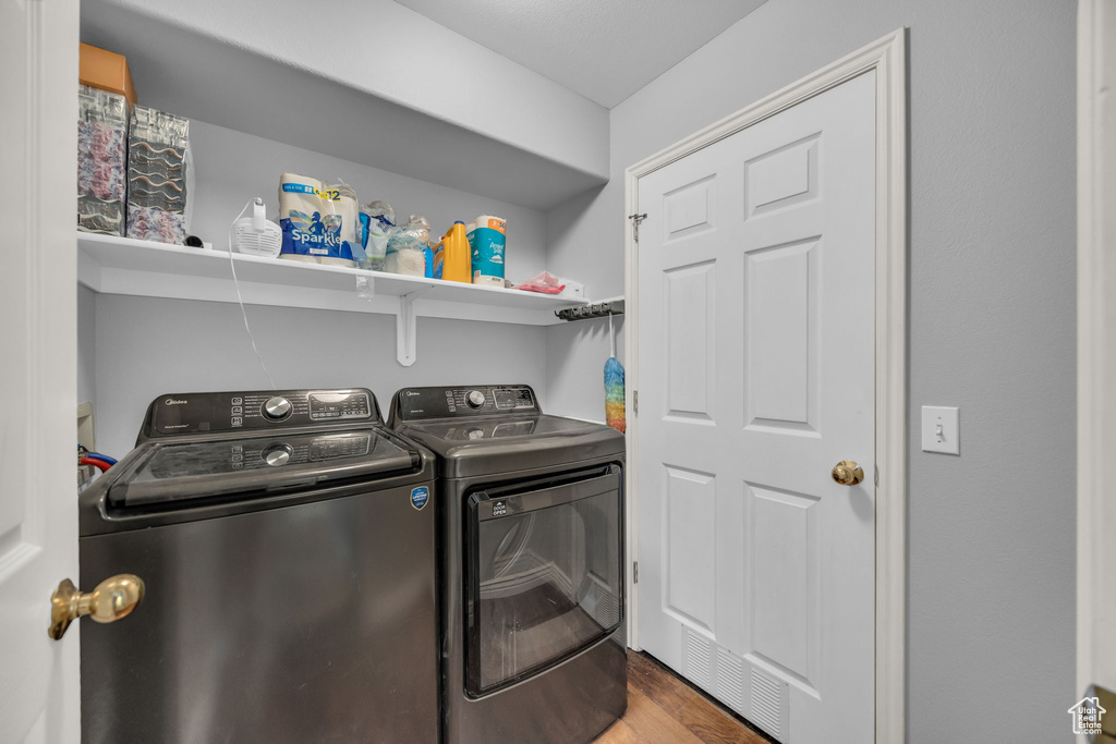 Laundry room with washer and clothes dryer and wood finished floors