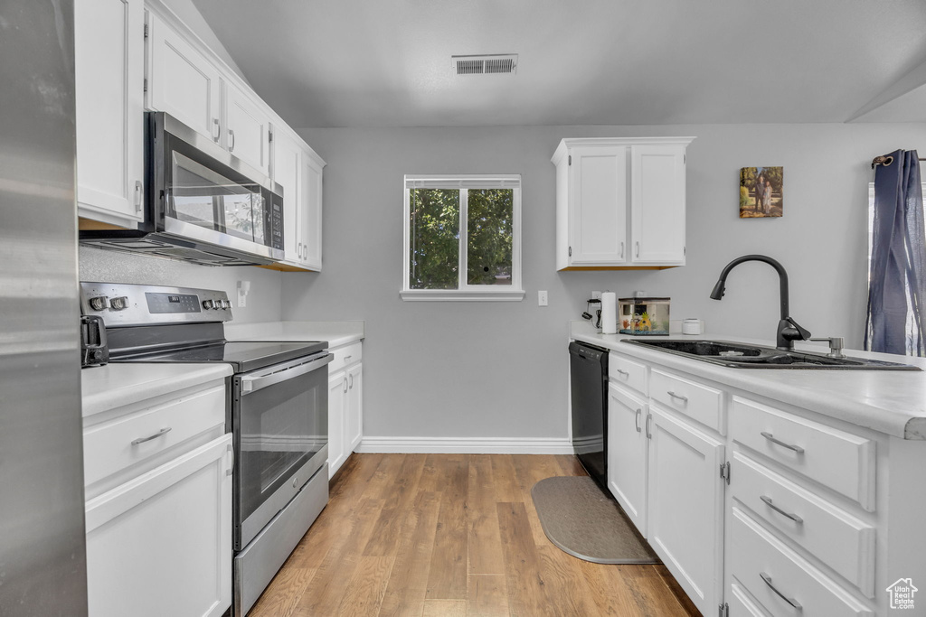 Kitchen featuring stainless steel appliances, a sink, light countertops, baseboards, and a peninsula