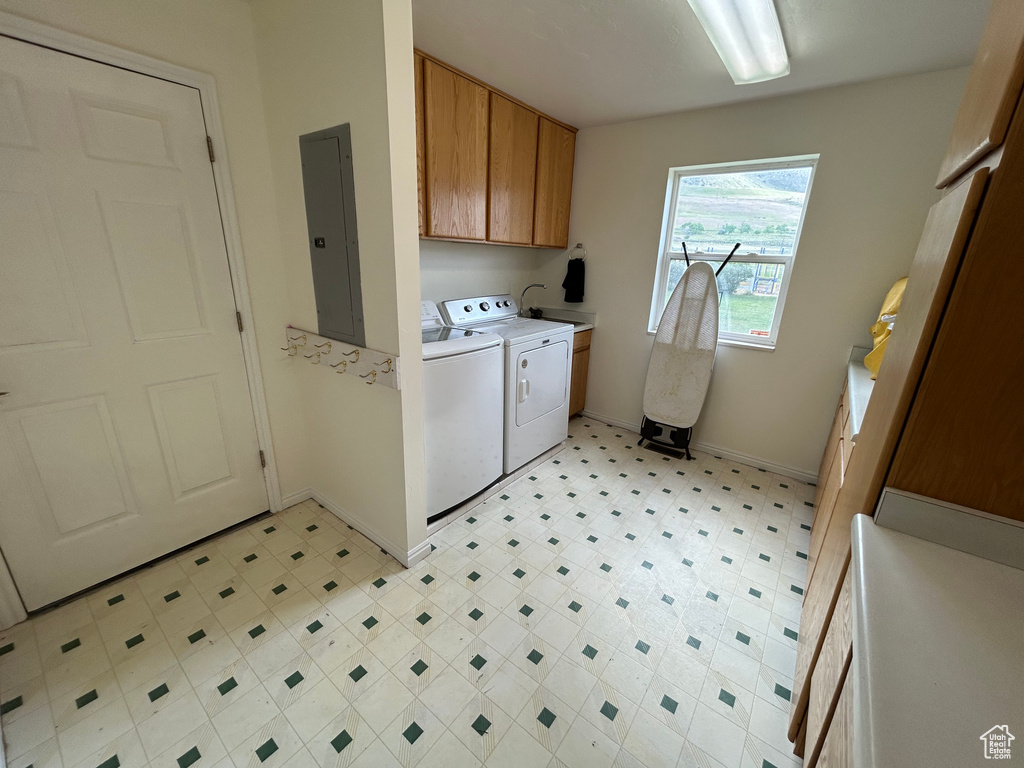 Laundry room featuring electric panel, cabinet space, independent washer and dryer, baseboards, and light flooring