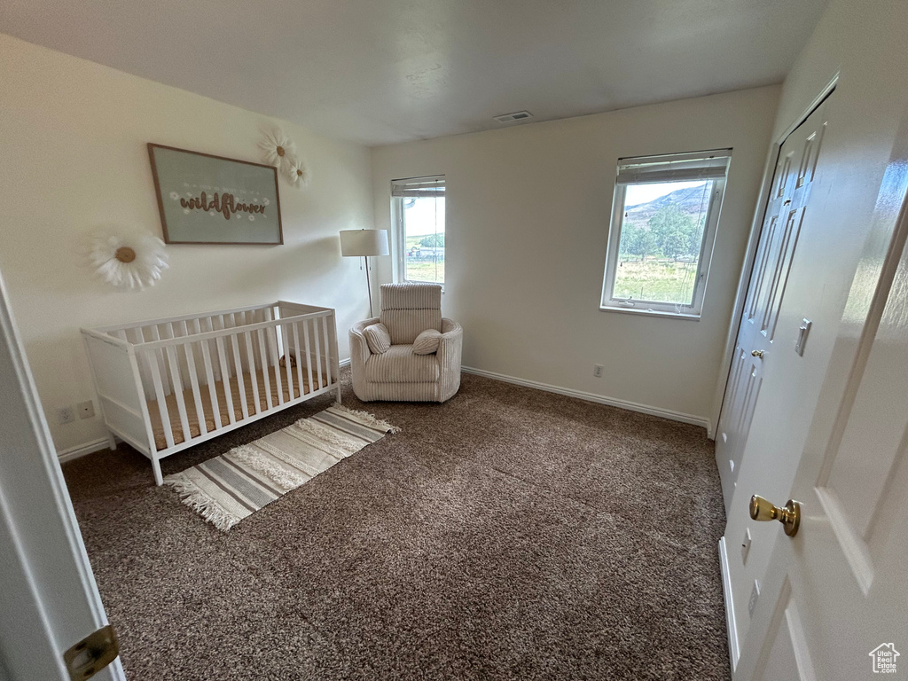 Bedroom featuring carpet, baseboards, and a nursery area