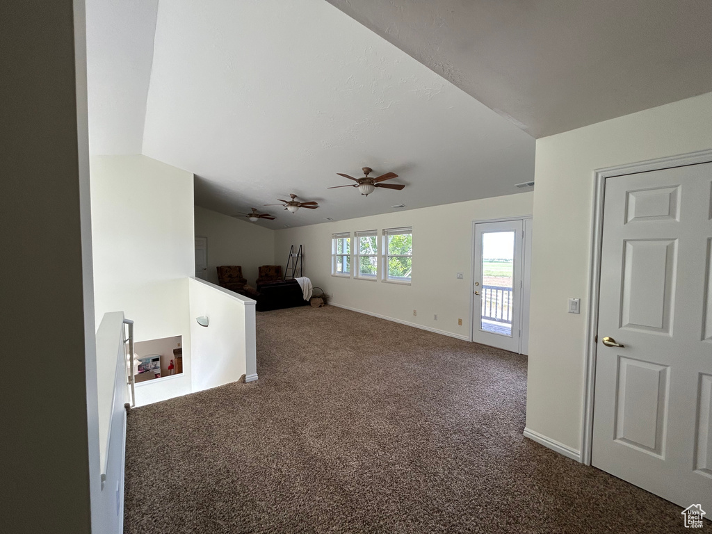 Carpeted spare room with vaulted ceiling, ceiling fan, and baseboards