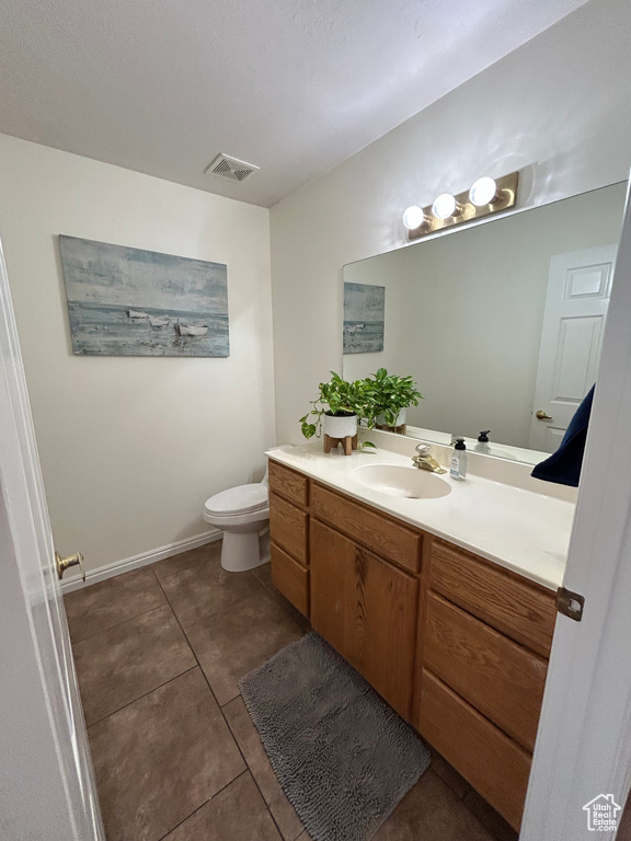 Bathroom with vanity, toilet, tile patterned floors, and baseboards