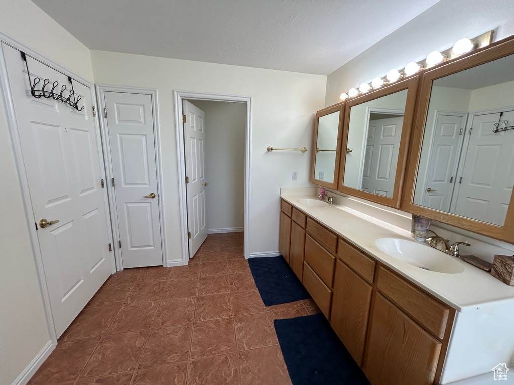 Full bathroom with double vanity, baseboards, and tile patterned flooring