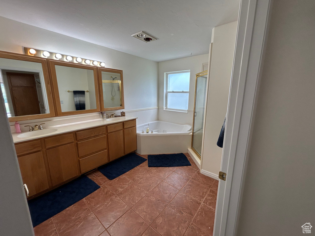 Bathroom featuring a bath, double vanity, a stall shower, and tile patterned floors