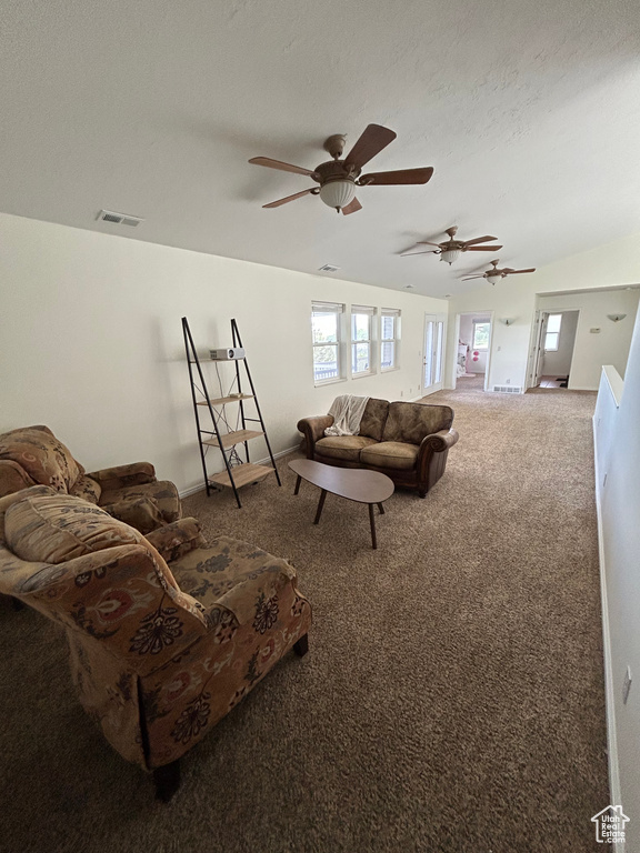 Carpeted living room with a ceiling fan and a textured ceiling