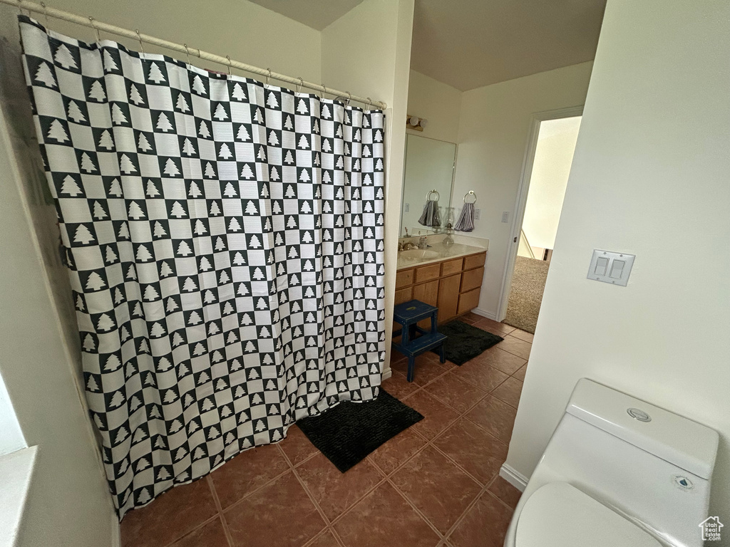 Bathroom with vanity, toilet, curtained shower, and tile patterned flooring