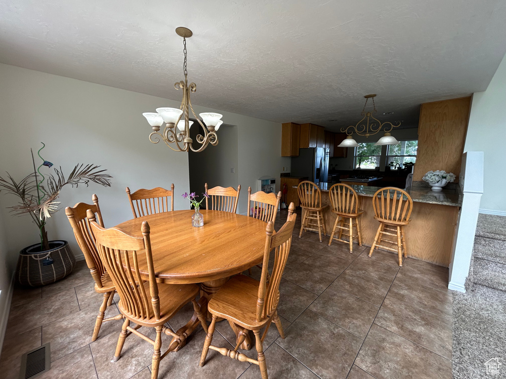 Tiled dining room with a chandelier, baseboards, and a textured ceiling