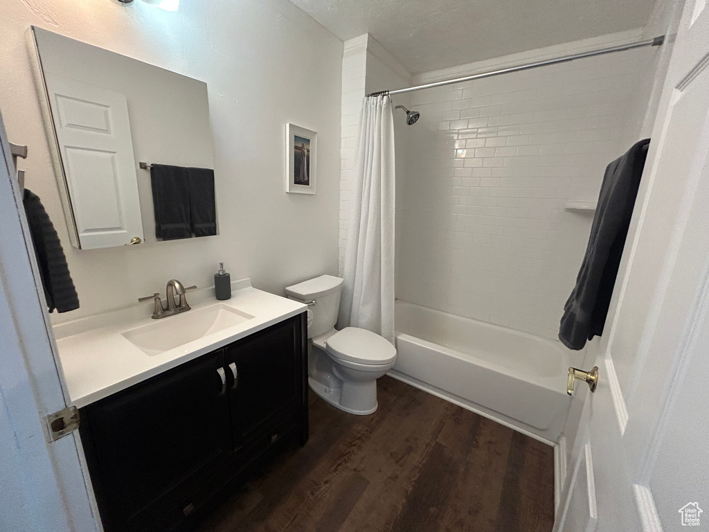 Full bath featuring wood finished floors, vanity, toilet, and shower / bath combination with curtain