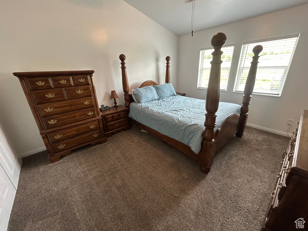 Bedroom featuring lofted ceiling, dark carpet, and baseboards