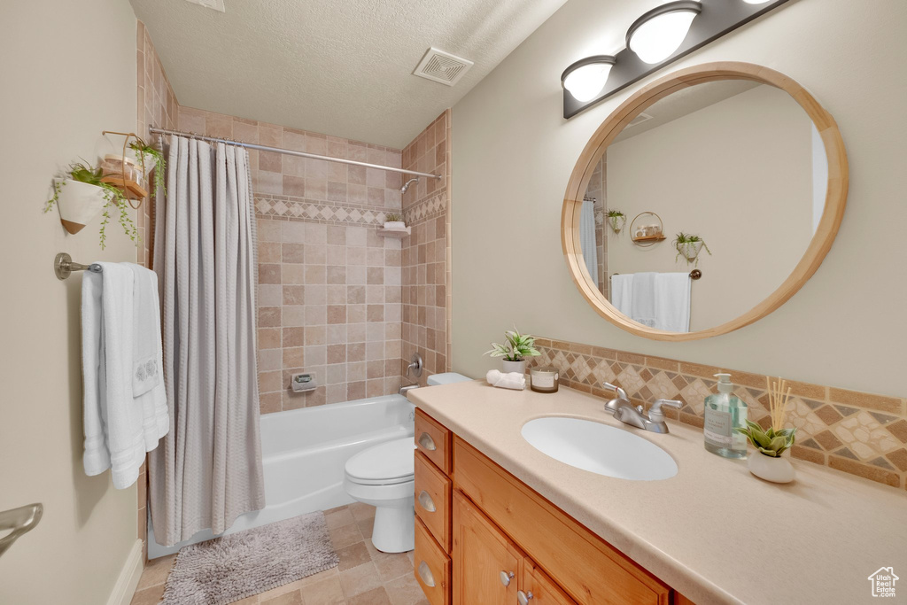 Full bathroom with vanity, shower / bath combination with curtain, toilet, a textured ceiling, and tasteful backsplash