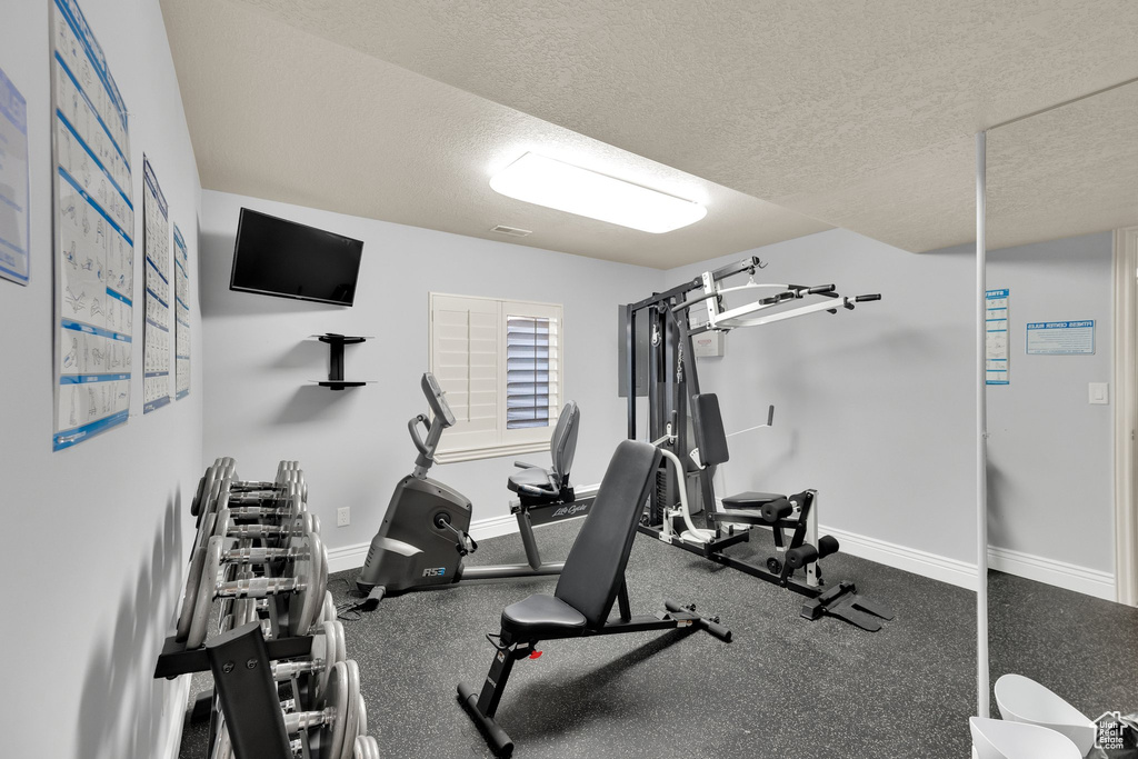 Exercise area featuring baseboards and a textured ceiling