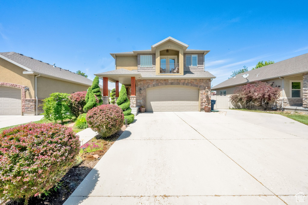 View of front of house featuring concrete driveway, stone siding, and a garage