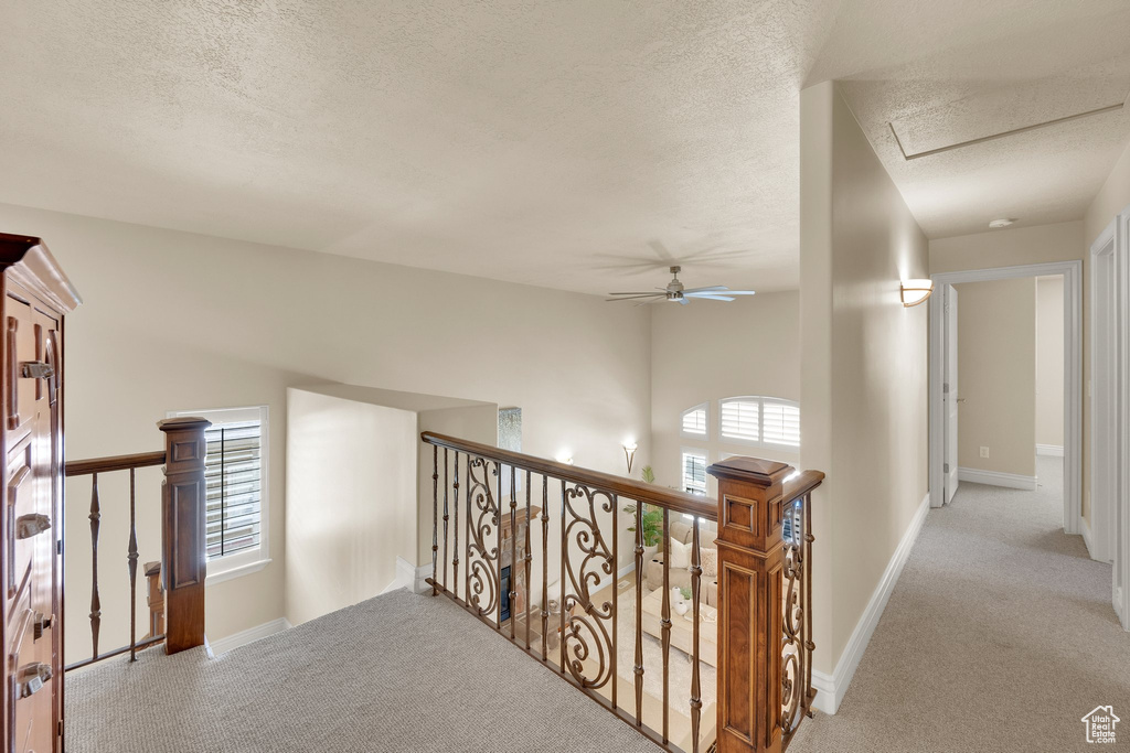 Hall featuring an upstairs landing, carpet floors, a textured ceiling, and baseboards
