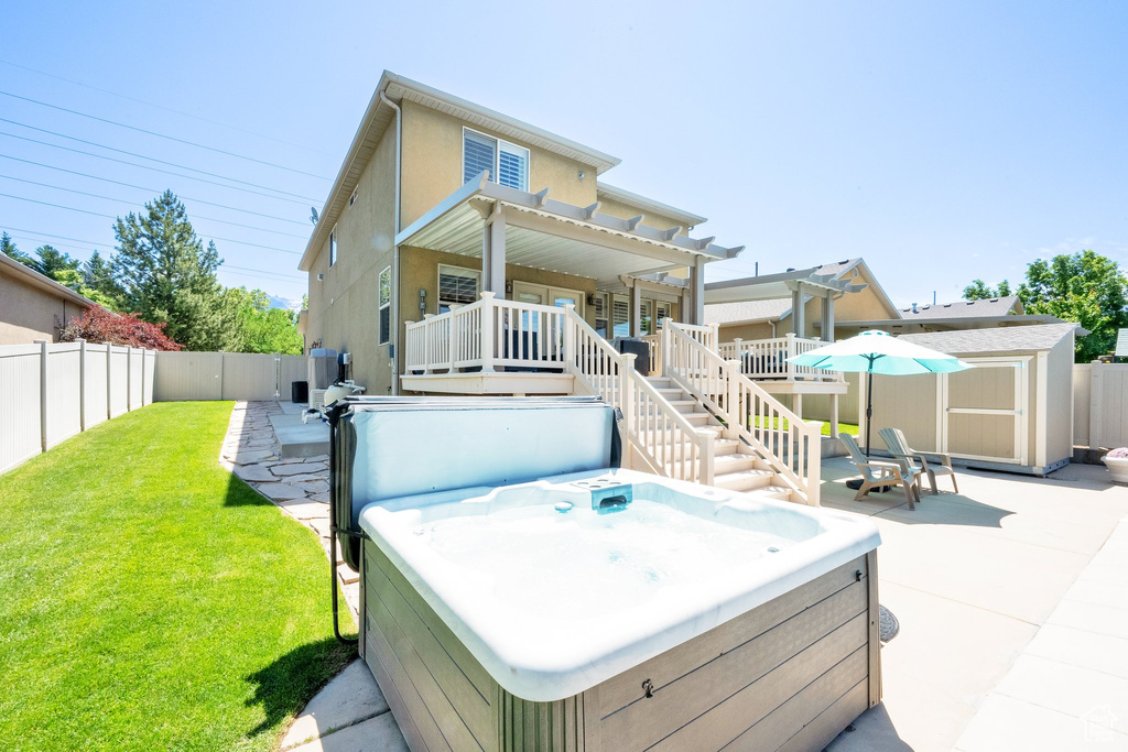Rear view of house with a hot tub, a pergola, a patio area, and stucco siding