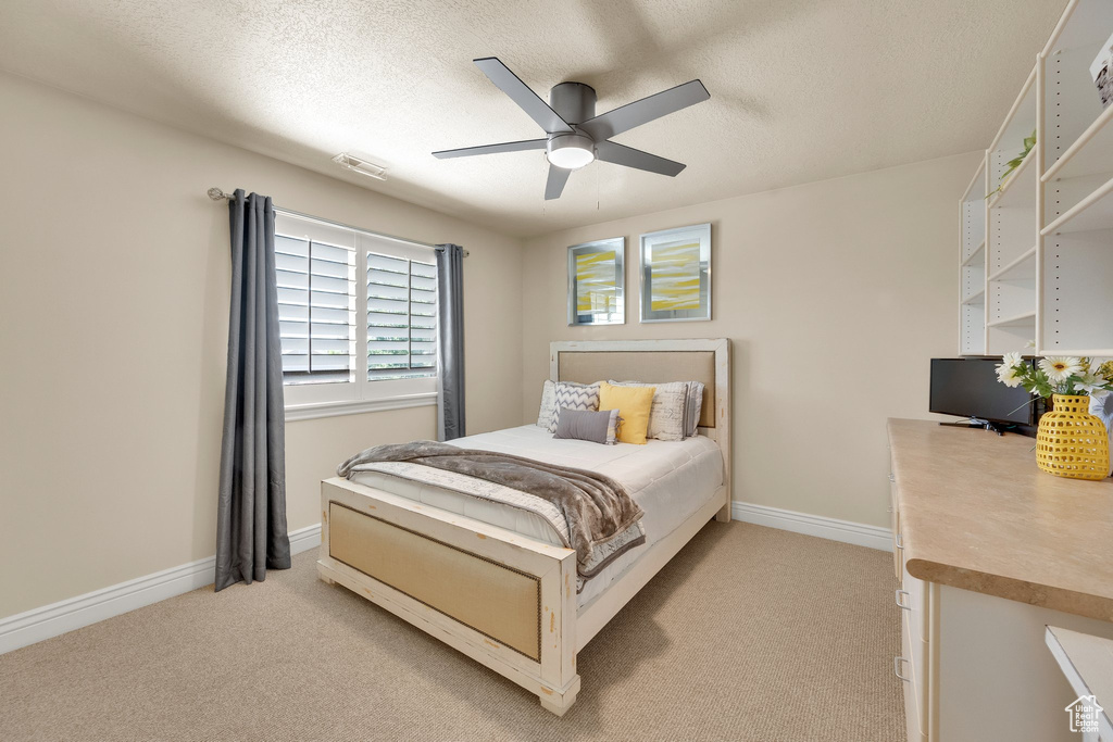 Bedroom featuring light colored carpet, baseboards, a ceiling fan, and a textured ceiling