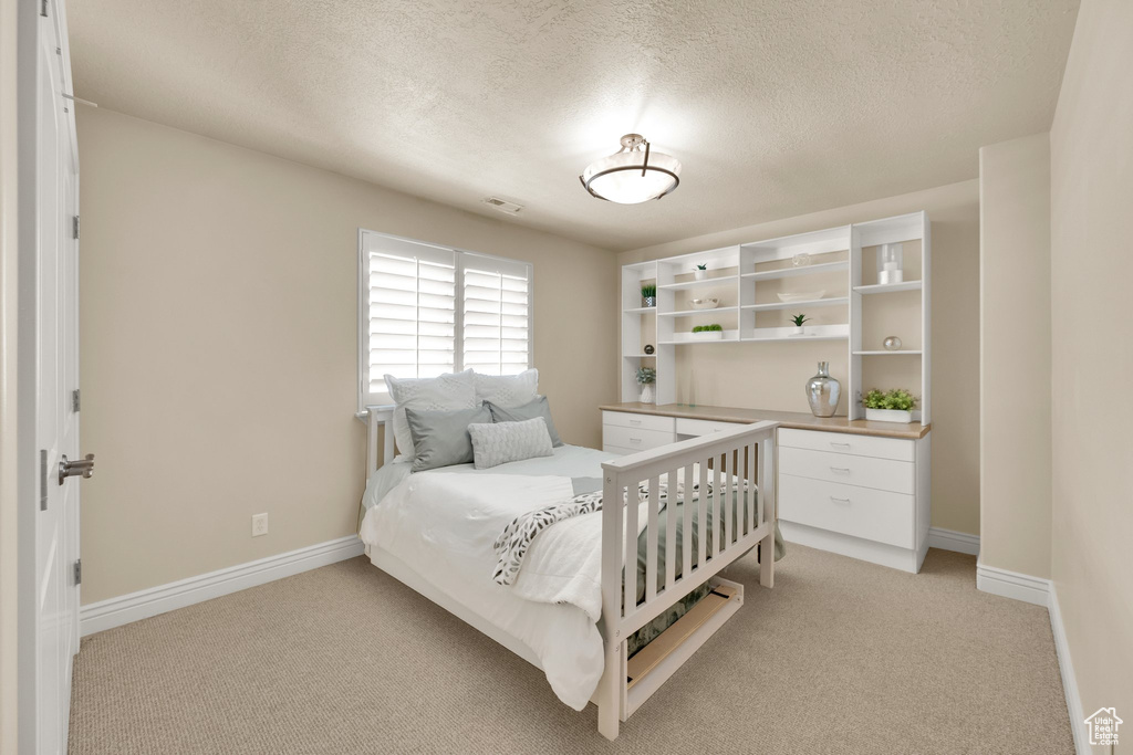 Bedroom with light carpet, baseboards, and a textured ceiling