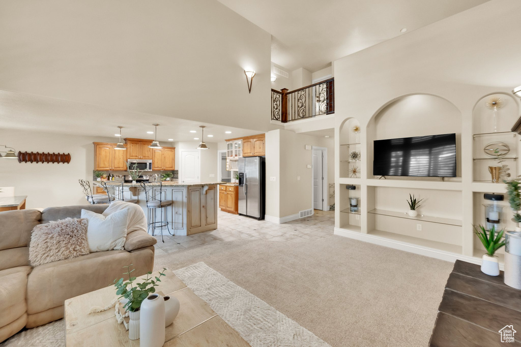 Living area featuring built in features, a towering ceiling, baseboards, light colored carpet, and recessed lighting