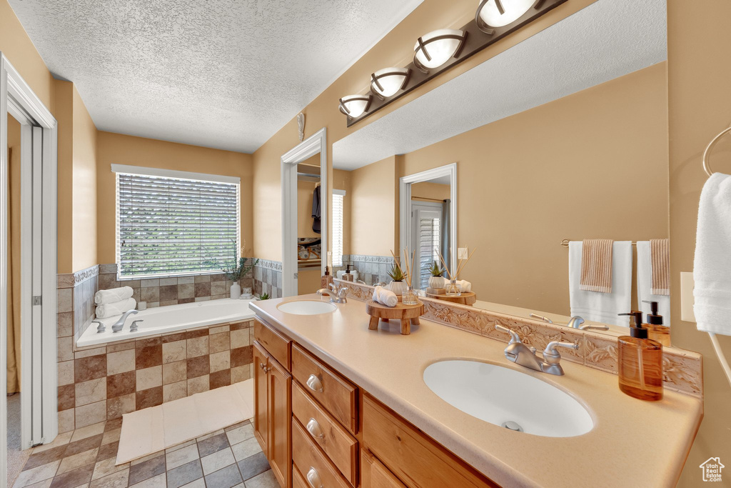 Bathroom with a garden tub, double vanity, and a textured ceiling