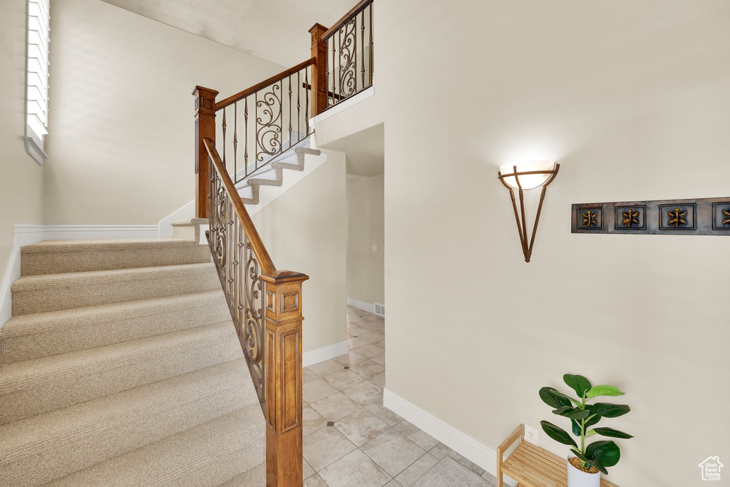 Stairway with tile patterned floors and baseboards