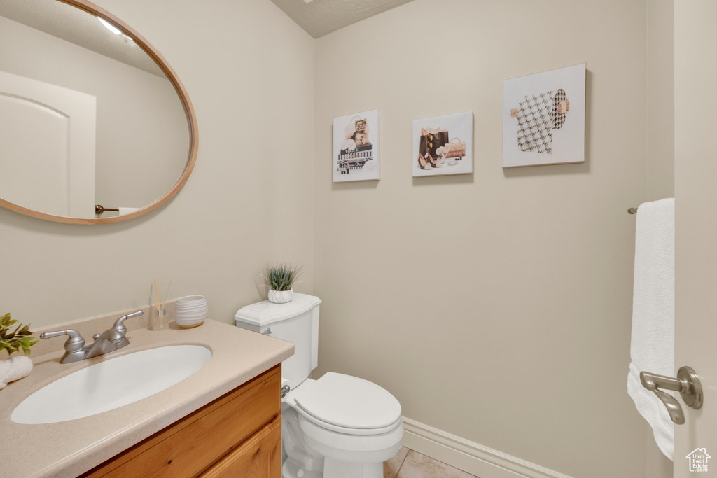 Bathroom with toilet, tile patterned floors, vanity, and baseboards