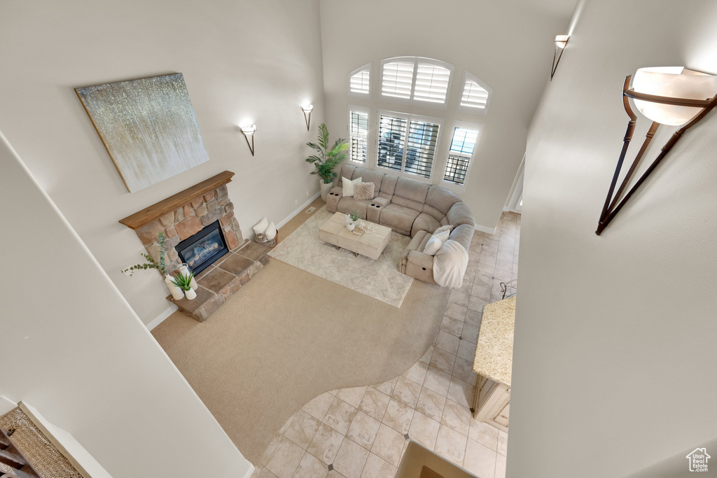 Living room featuring baseboards, a stone fireplace, and a towering ceiling
