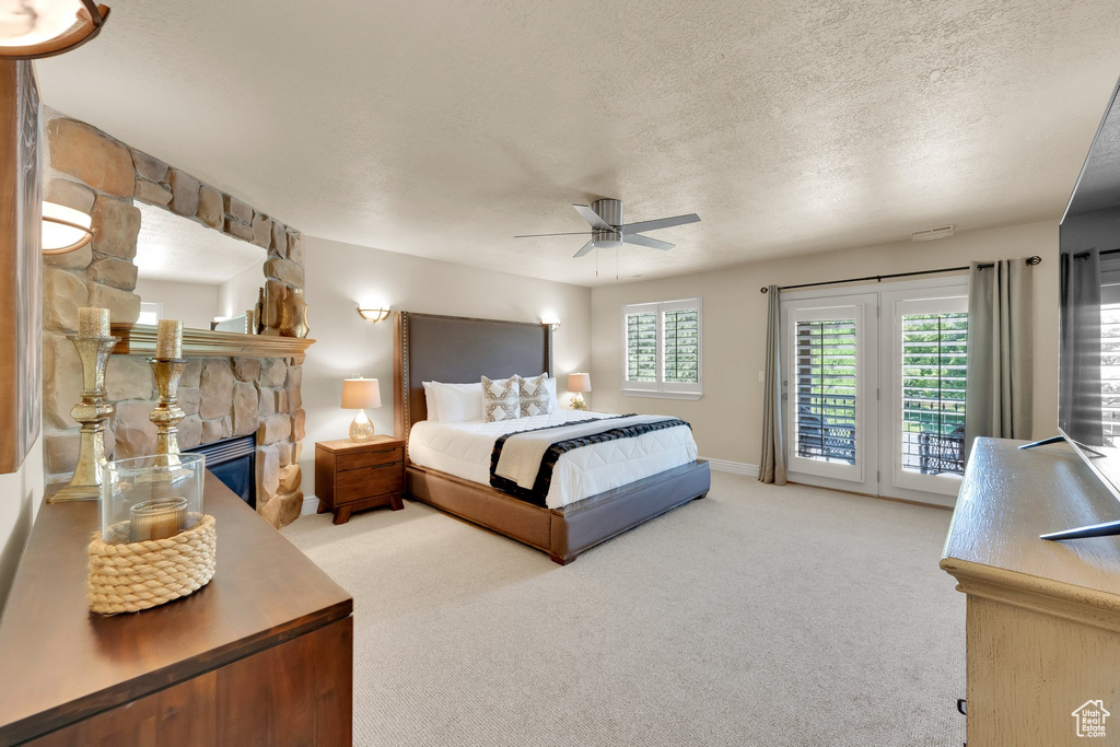 Carpeted bedroom with access to exterior, a fireplace, a textured ceiling, and ceiling fan