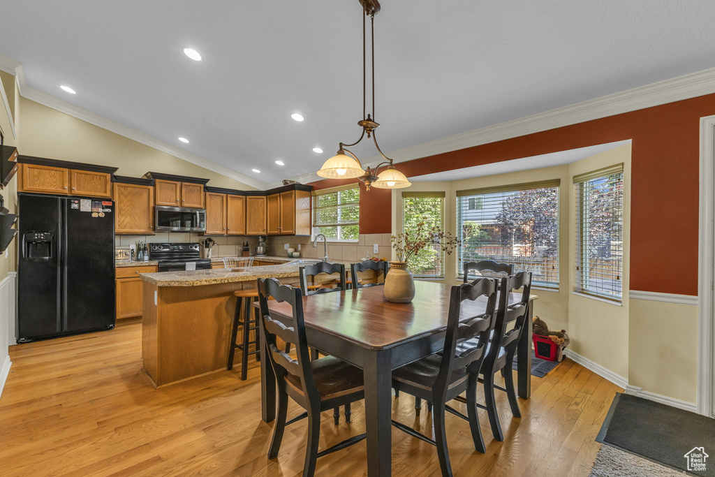 Dining room with ornamental molding, light wood-style flooring, recessed lighting, vaulted ceiling, and baseboards