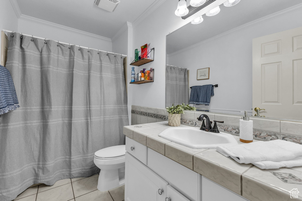 Bathroom with vanity, toilet, tile patterned floors, ornamental molding, and tile walls