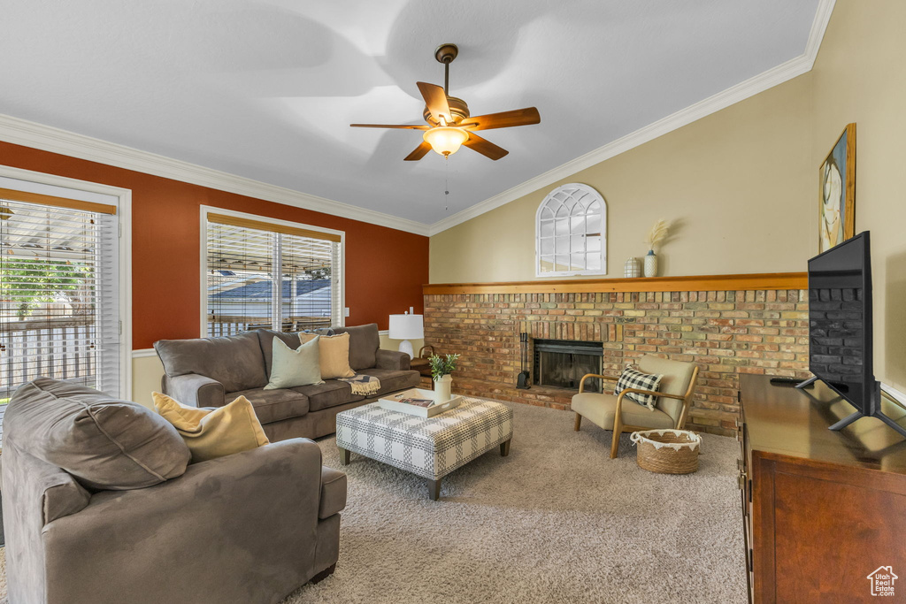 Living area featuring a fireplace, crown molding, ceiling fan, and carpet floors
