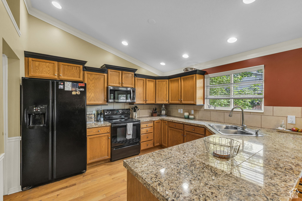 Kitchen with black appliances, a sink, lofted ceiling, a peninsula, and light wood-style flooring