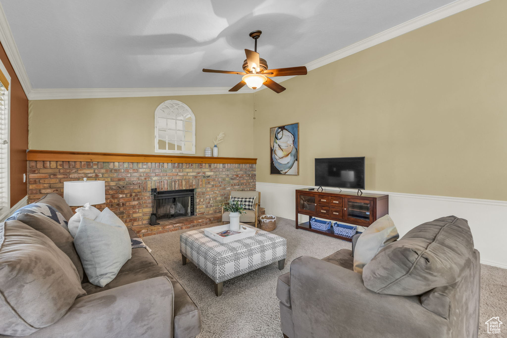 Carpeted living area featuring ornamental molding, a ceiling fan, and a fireplace