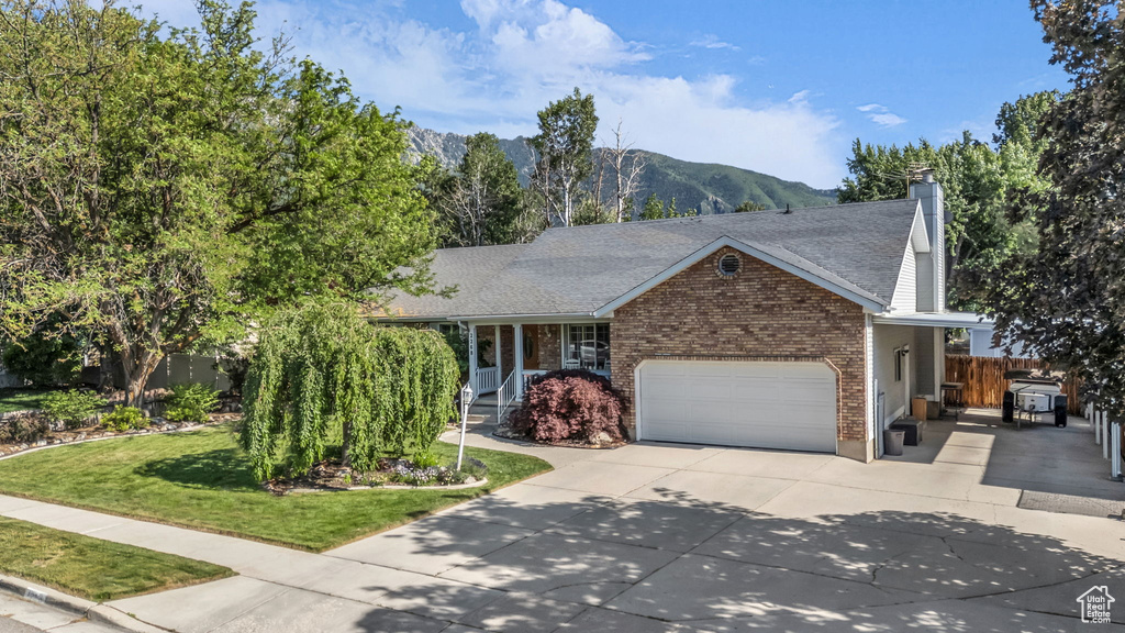 View of front facade with a garage, a mountain view, driveway, brick siding, and a chimney