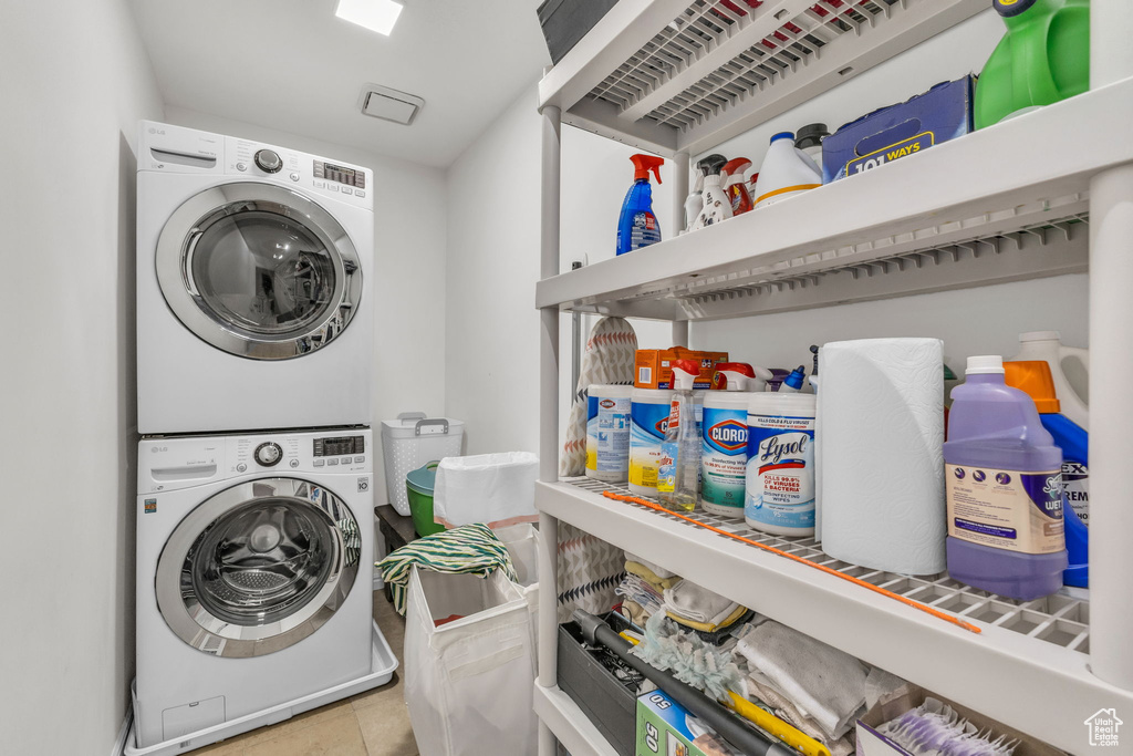 Washroom with stacked washing machine and dryer and tile patterned floors