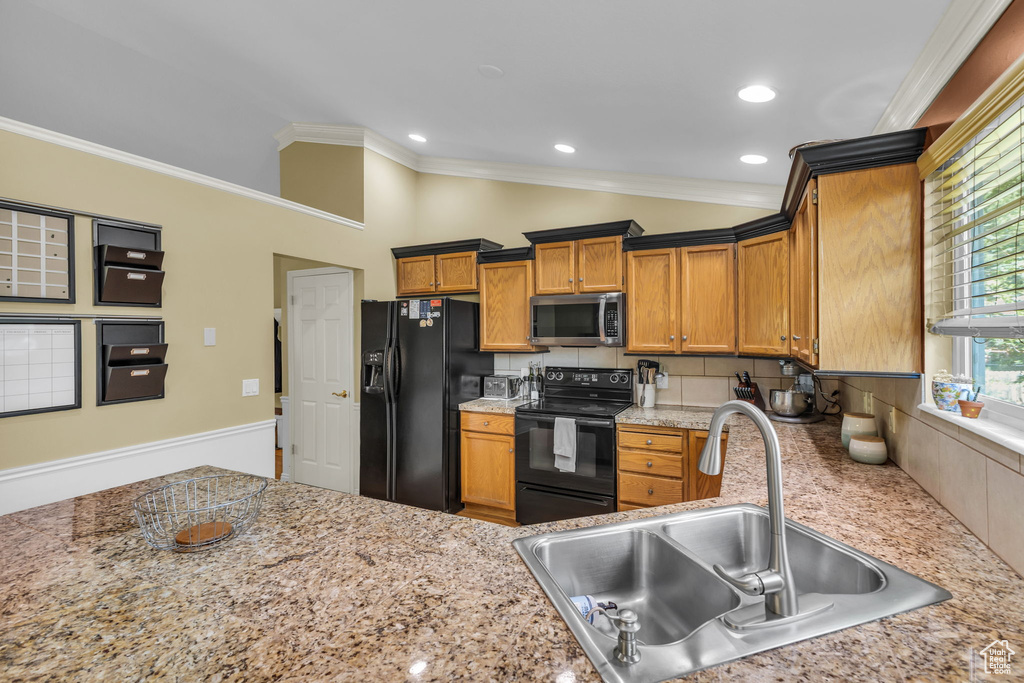 Kitchen with black appliances, a sink, crown molding, brown cabinetry, and decorative backsplash