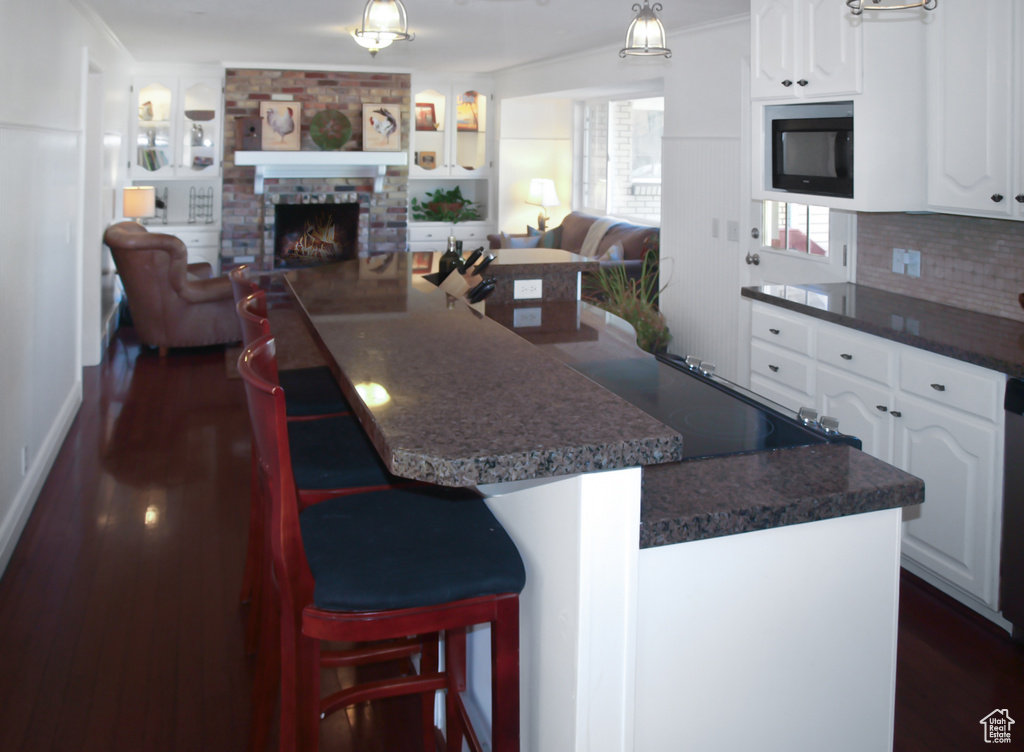 Kitchen with open floor plan, dark countertops, dark wood-type flooring, and white cabinetry