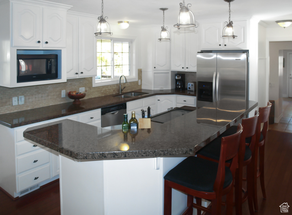 Kitchen with a sink, appliances with stainless steel finishes, backsplash, white cabinets, and crown molding