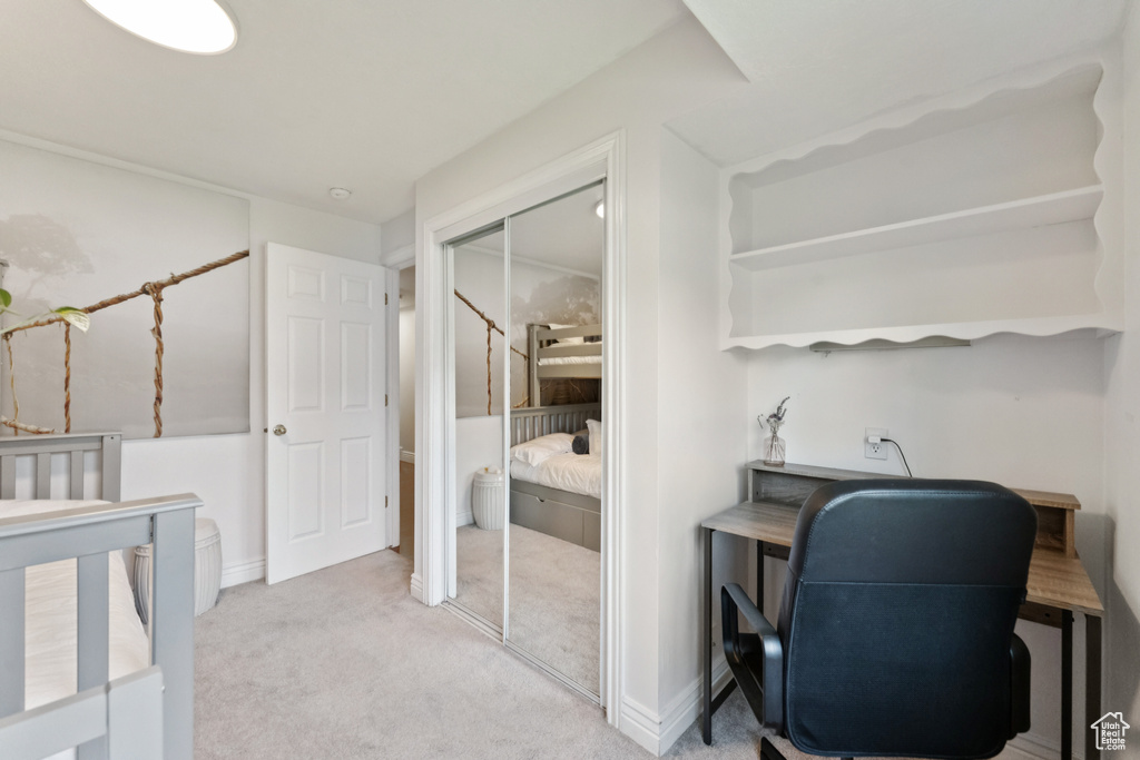 Carpeted bedroom with a closet and an office area
