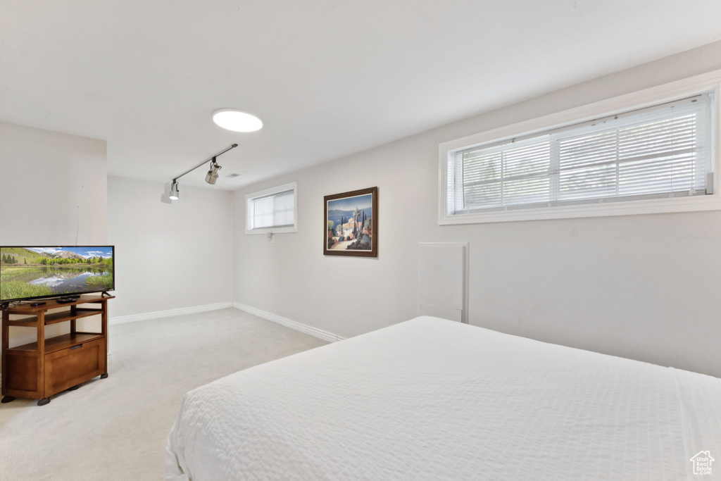 Bedroom with light colored carpet and track lighting