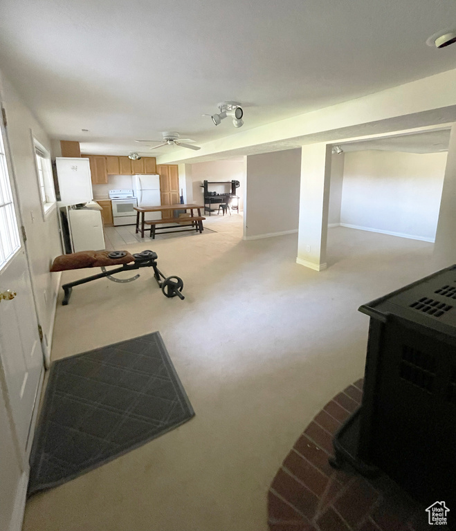 Exercise area featuring light colored carpet, ceiling fan, and baseboards