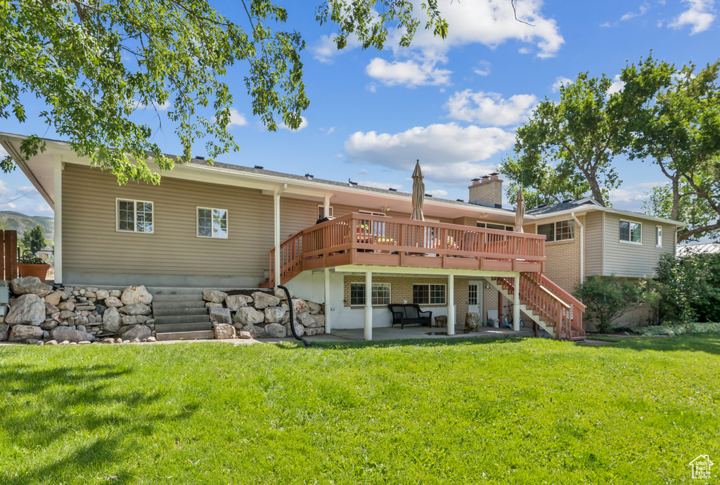Back of house with stairs, a wooden deck, a patio area, a yard, and a chimney