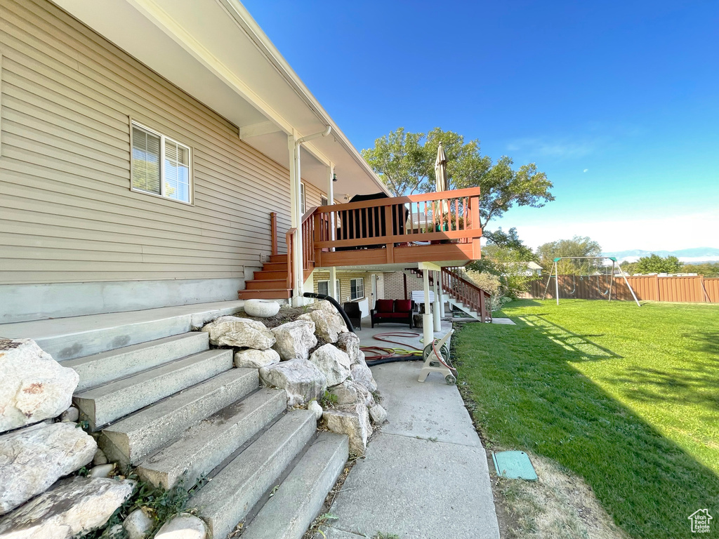 View of side of property with stairs, a patio, a wooden deck, and a playground