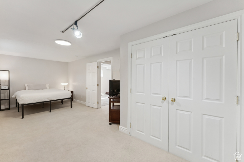 Bedroom featuring light colored carpet, a closet, and track lighting