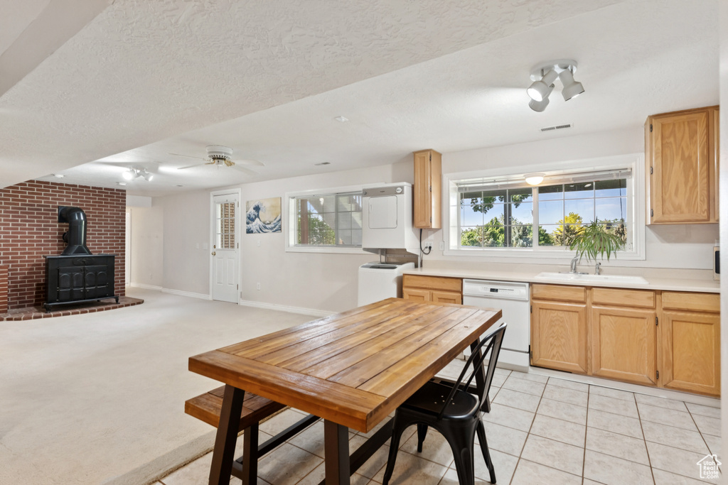 Kitchen with dishwasher, a wood stove, light countertops, a ceiling fan, and a textured ceiling
