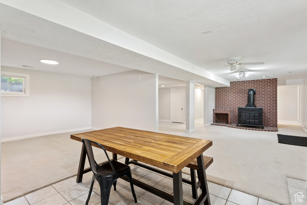 Dining room with light carpet, a wood stove, light tile patterned floors, and a textured ceiling