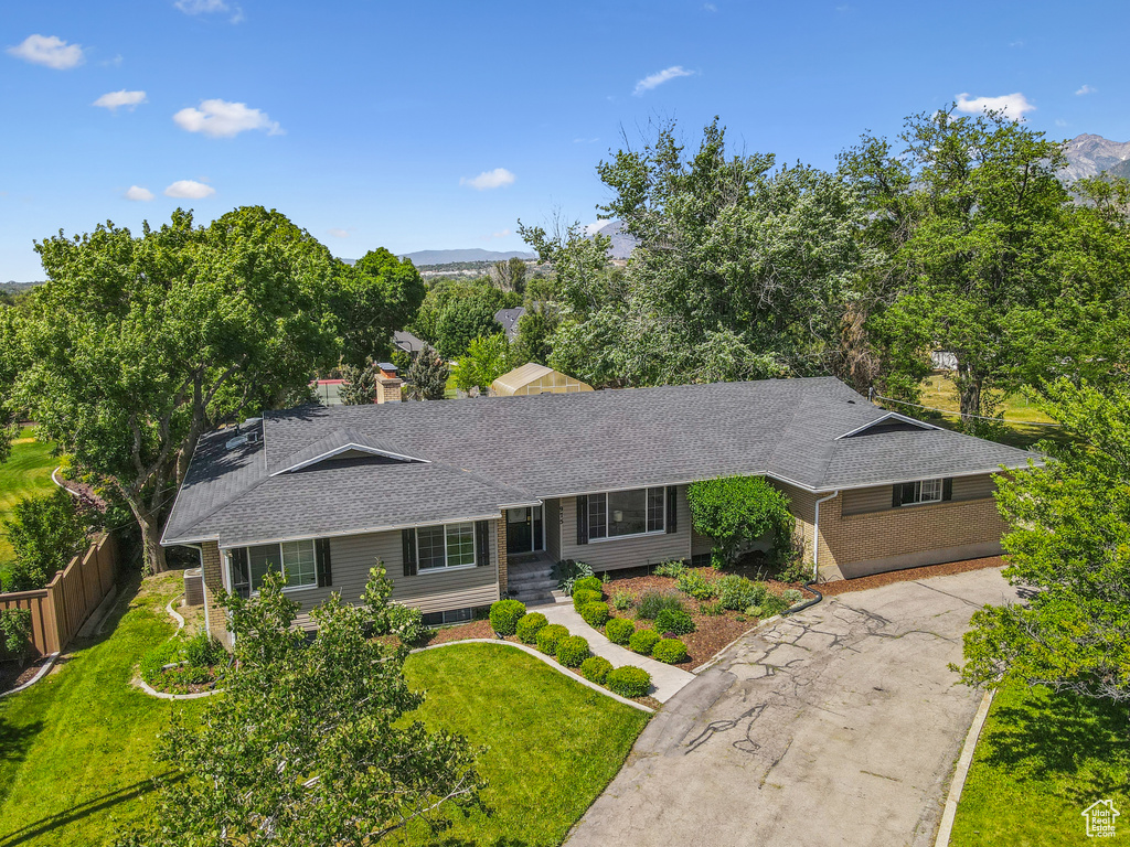 Ranch-style home featuring a shingled roof, brick siding, a mountain view, and a chimney