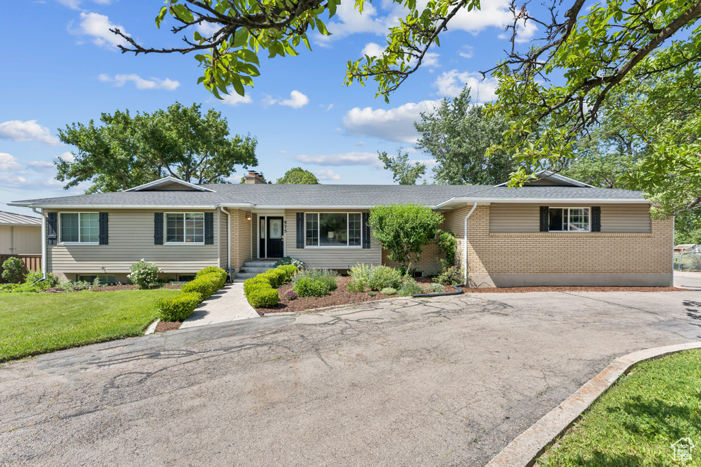Ranch-style house with brick siding, a front yard, a chimney, and a shingled roof