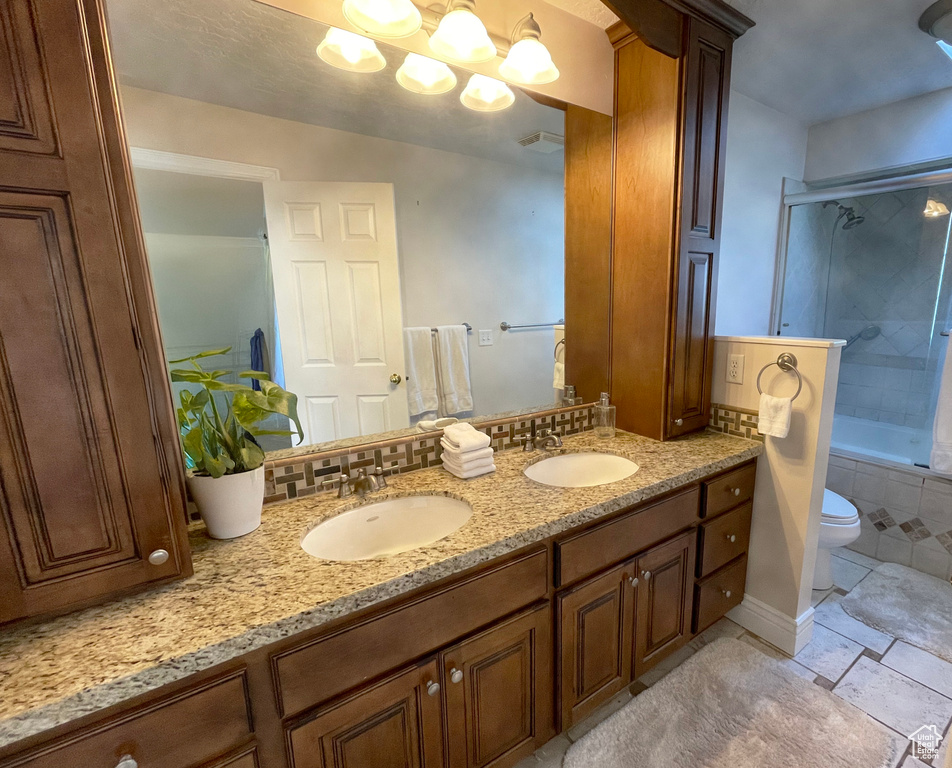 Full bath with double vanity, toilet, shower / tub combination, and a chandelier