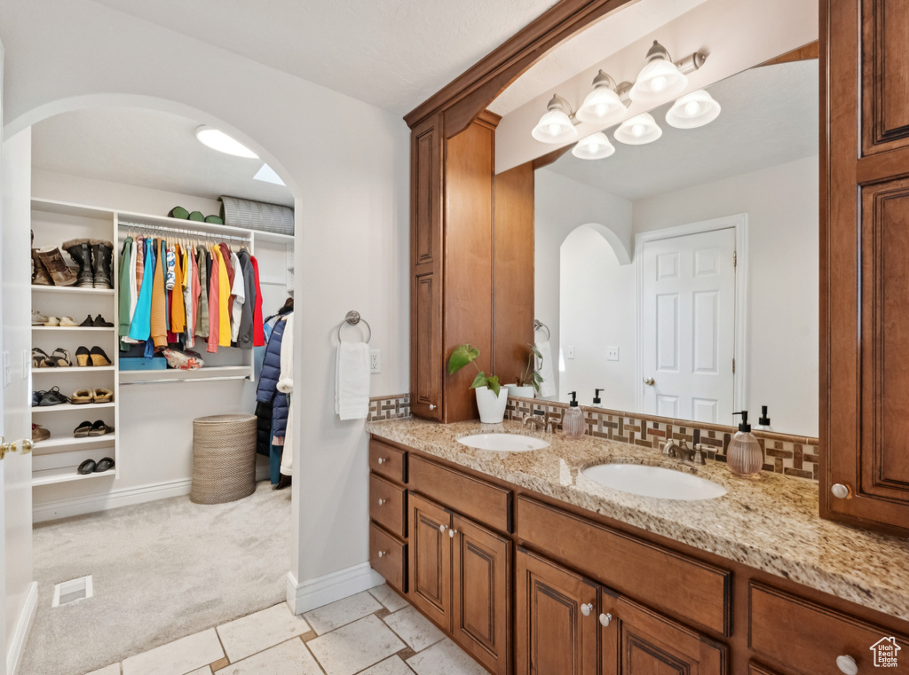 Bathroom featuring double vanity and a walk in closet