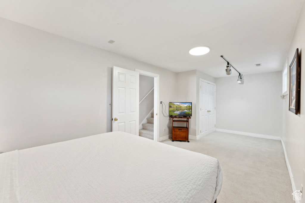 Bedroom with light colored carpet and rail lighting