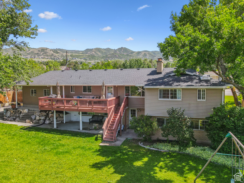 Back of property with a patio, a deck with mountain view, a chimney, stairway, and brick siding